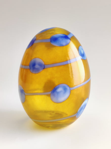 Decorative glass egg with blue patterns on a white background