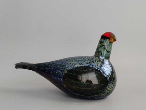 Glass bird figurine with a speckled pattern on a plain background