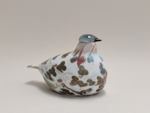 Decorative glass bird with floral patterns on a beige background design Oiva Toikka