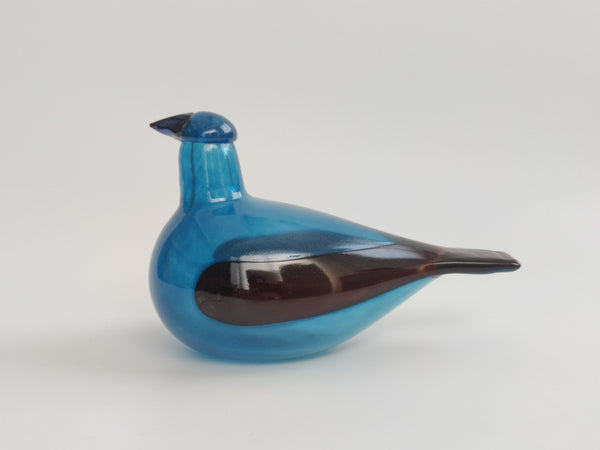 Blue glass bird-shaped object on a light gray background