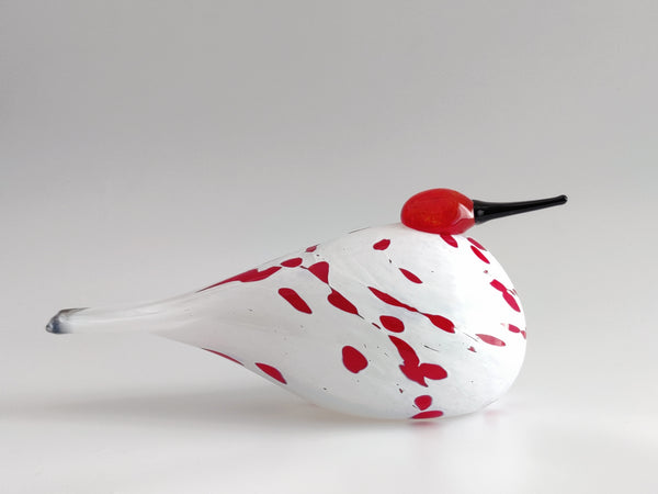 Glass bird figurine with red spots on a white background