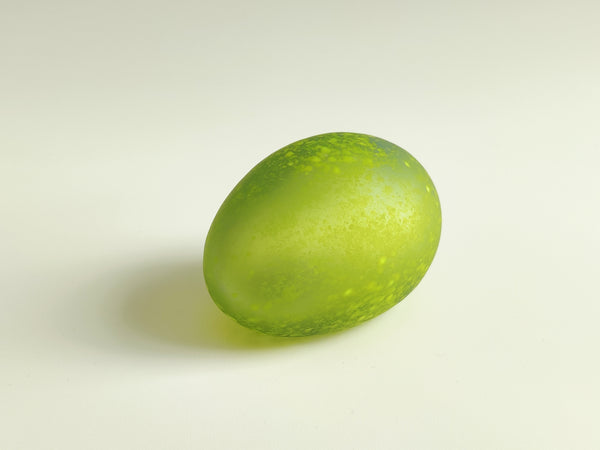 A translucent light green glass egg with a frosted, speckled texture, photographed on a clean off-white background.