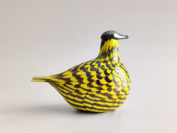 A decorative bird figurine with a bright yellow body covered in black and gray scalloped feather-like patterns, standing on a light gray background.